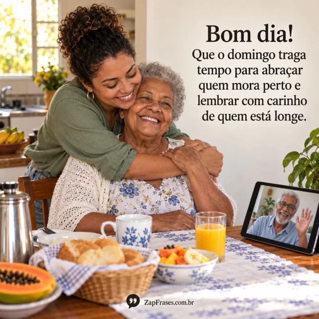 Avó e neta se abraçam em cozinha ensolarada, celular mostra chamada de vídeo com familiar distante sem texto legível. Arte com mensagem de bom dia, domingo.